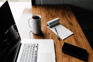 Cup Of Coffee, Notepad and Pen, and Laptop On A Table