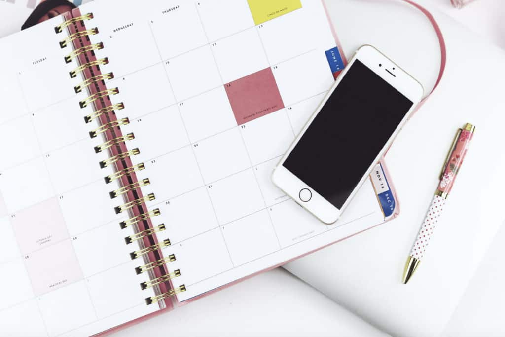 Calendar planner open with pen and cellphone on table