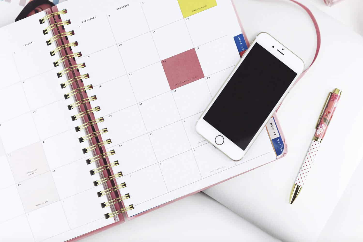 Calendar planner open with pen and cellphone on table