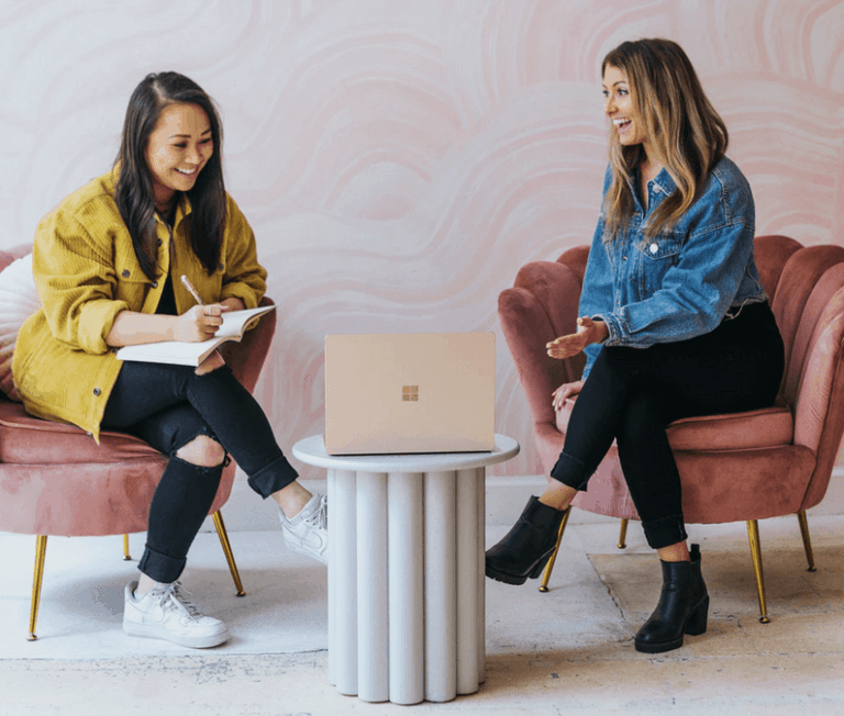 two women sitting at laptop discussing notes