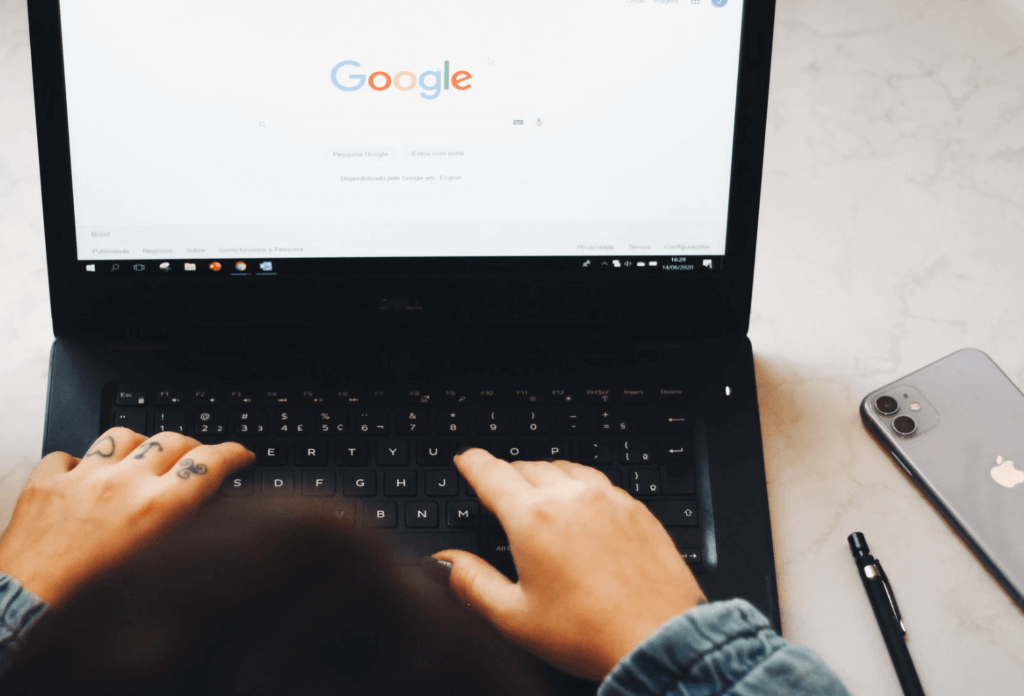 Woman typing on laptop with Google homepage on screen