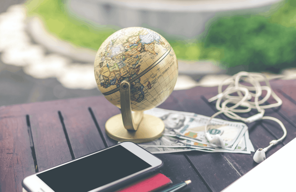 Table with cellphone, stationary, globe, money, and headphones