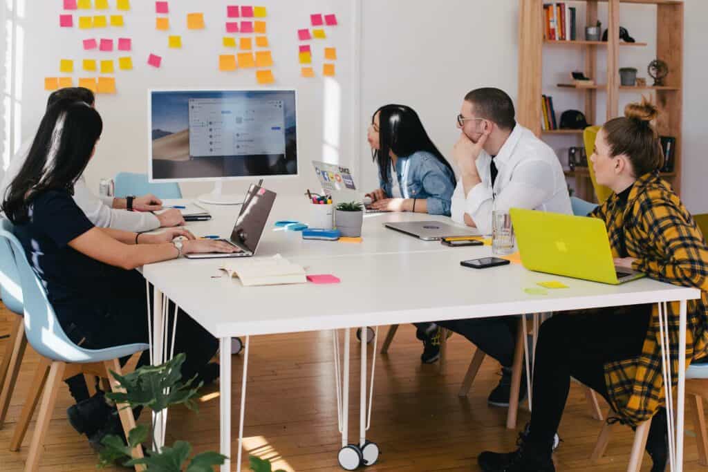 Employees in a meeting sitting around a table and looking at screen