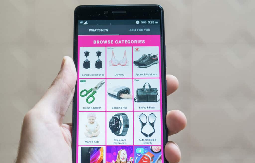 Person holding cellphone showing ecommere website landing page with categories