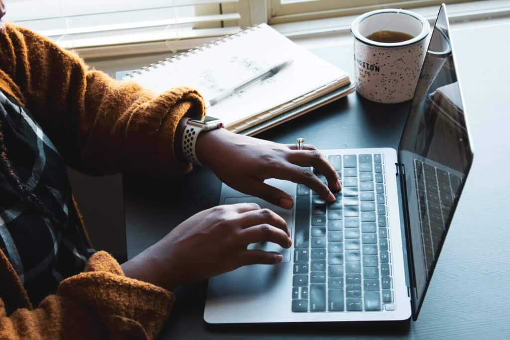 Woman sitting at desk, writing on laptop