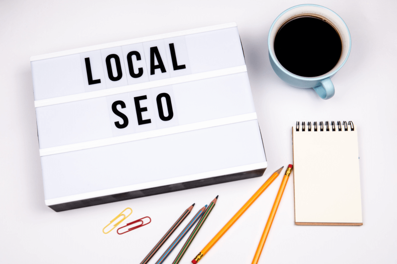 Sign that says local SEO on a table with coffee cup, notepad, and pencils