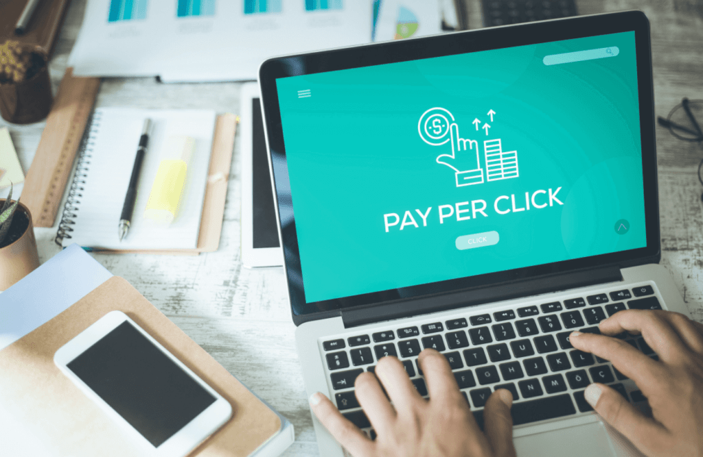 Person typing on laptop with pay-per-click landing page on screen