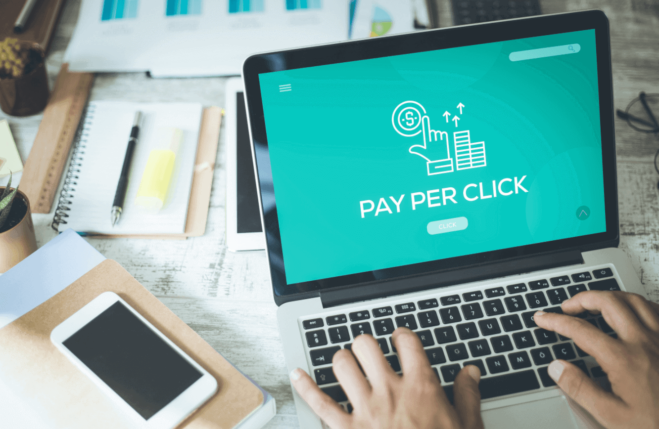 Person typing on laptop with pay-per-click landing page on screen