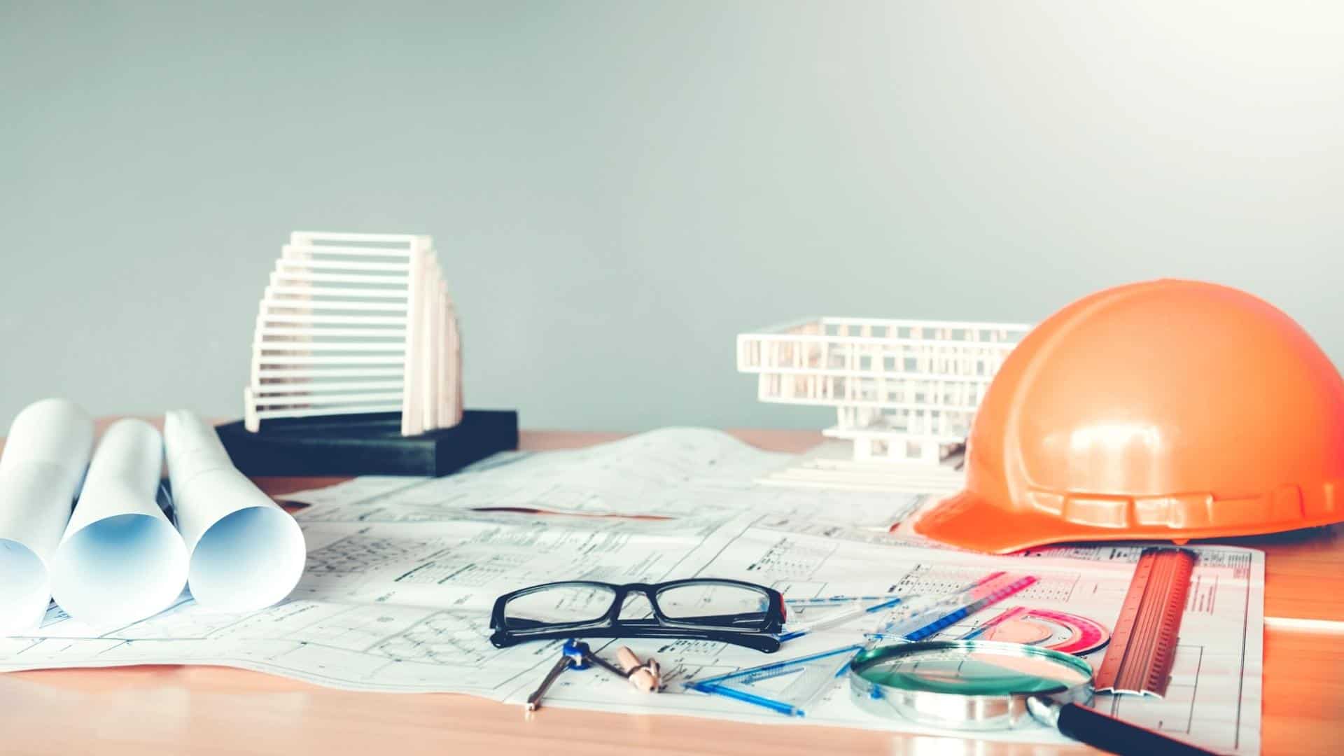 A desk in an office with blueprints and stationery