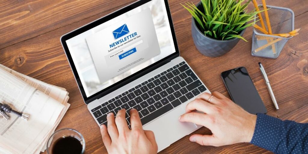 A person typing on a laptop with a newsletter sign-up page on the screen